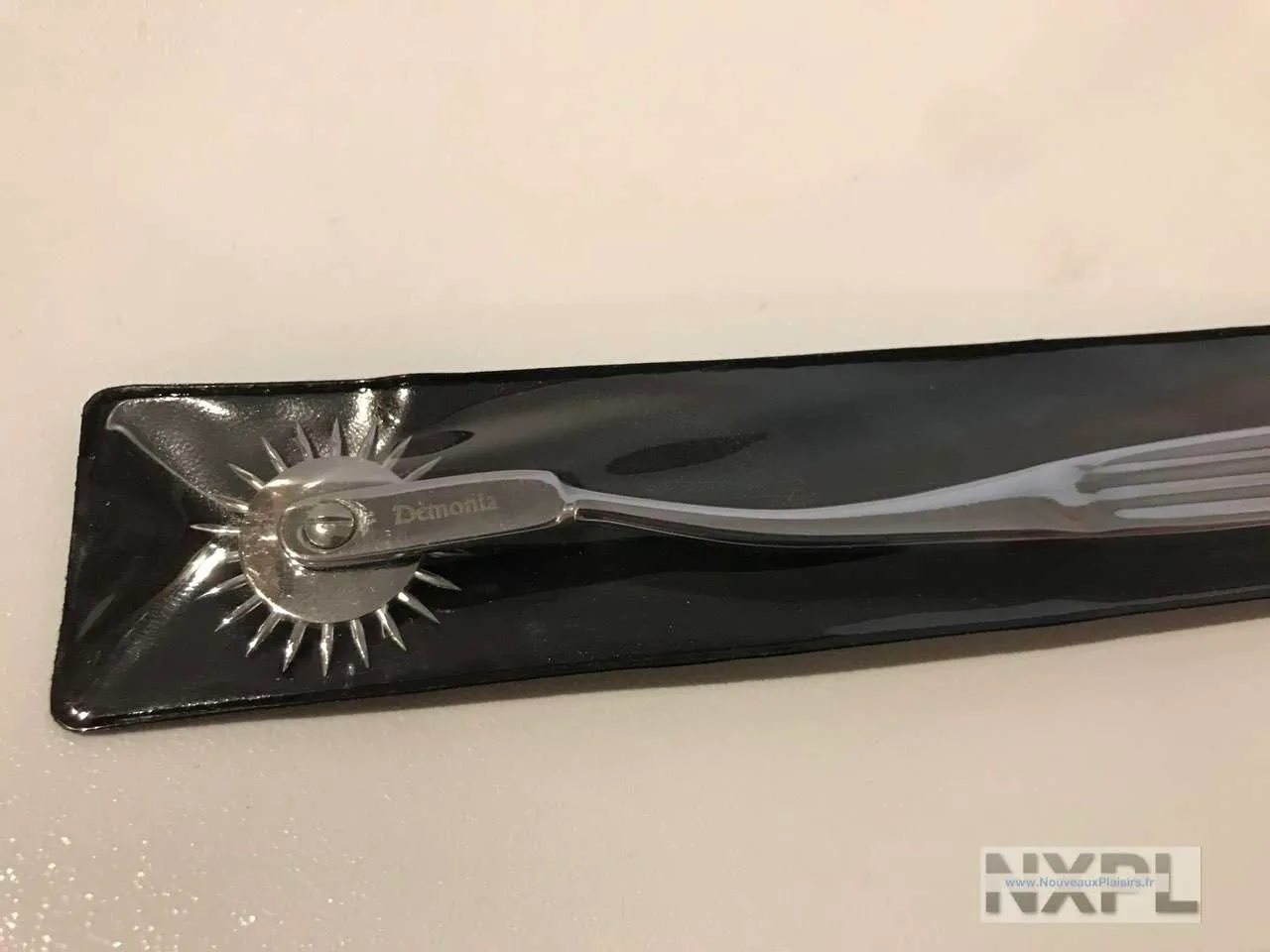 Roue à pics Dèmonia ou roulette de Wartenberg en métal argenté posée sur un fond gris