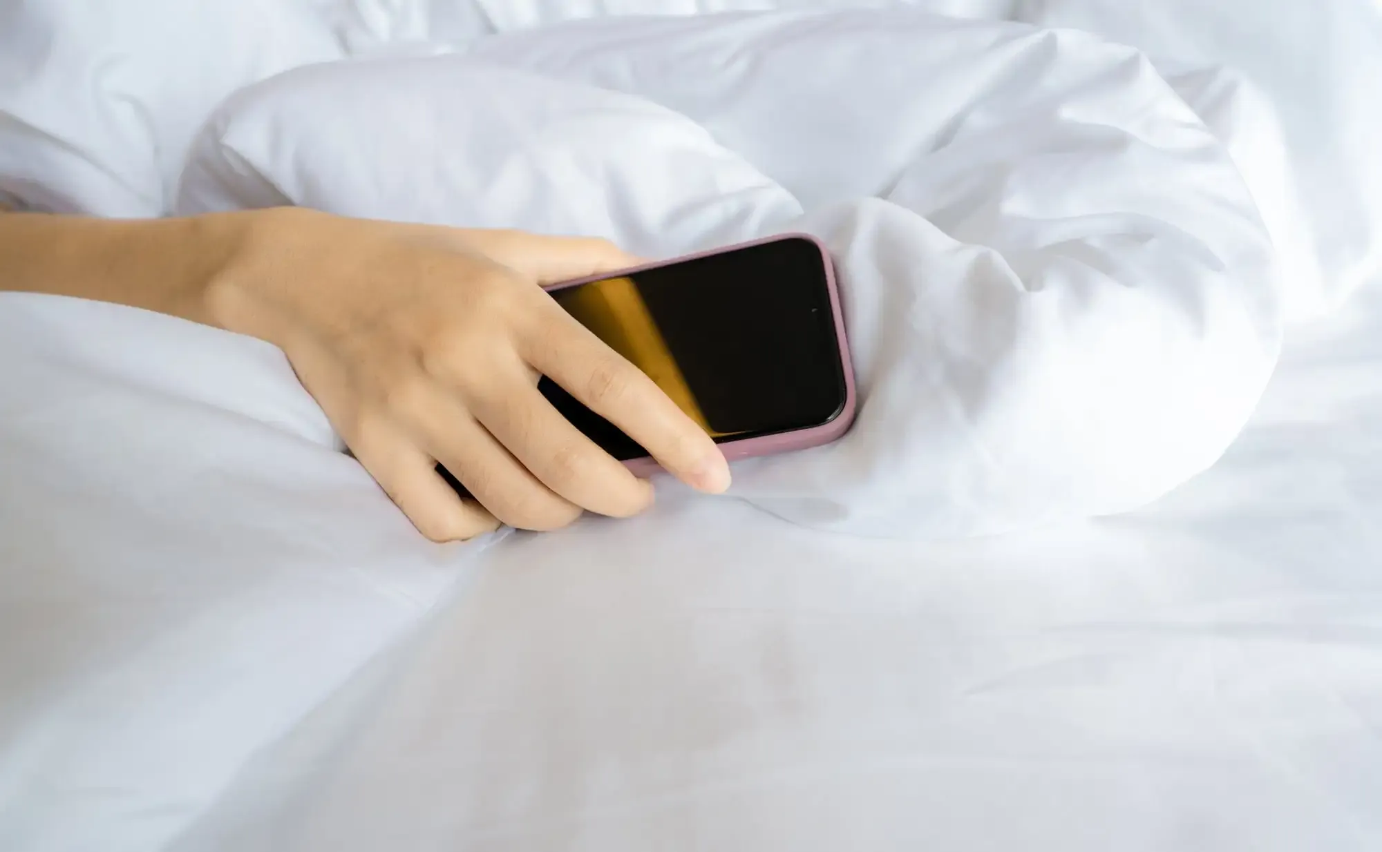 Un téléphone posé sur un lit, symbolisant une interruption dans l'intimité