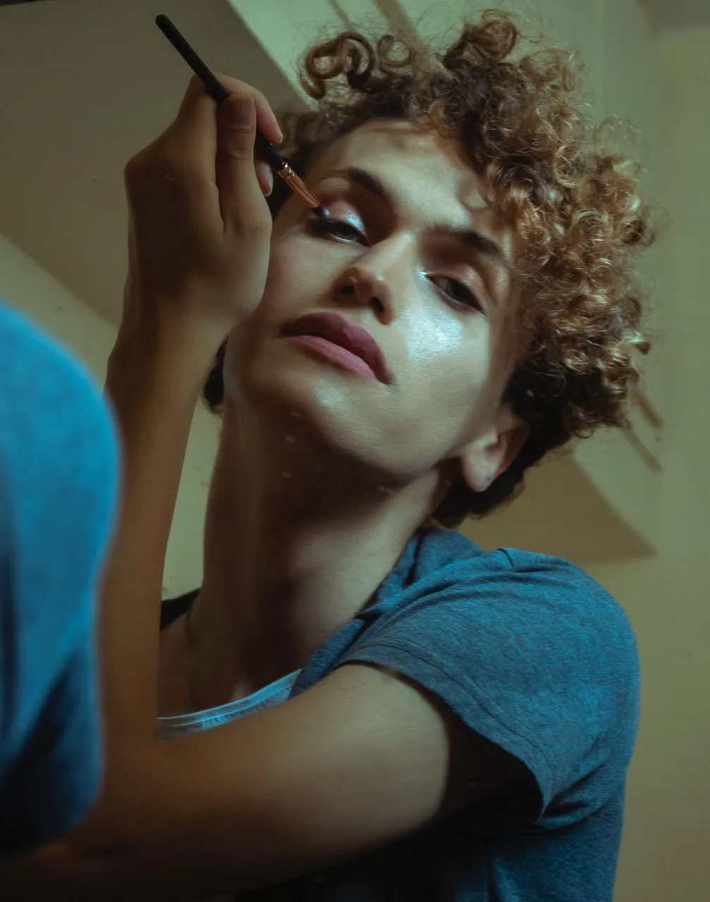 Une femme transgenre se préparant devant un miroir, évoquant la douceur et la féminité.