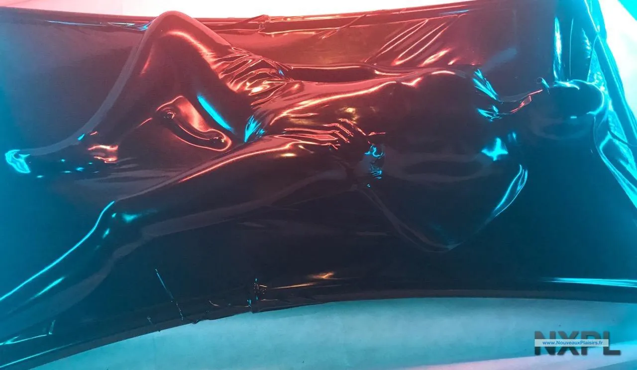 Individu totalement immobilisé dans le sac en latex noir du Vac Bed Eurocatsuits avec son embout respiratoire